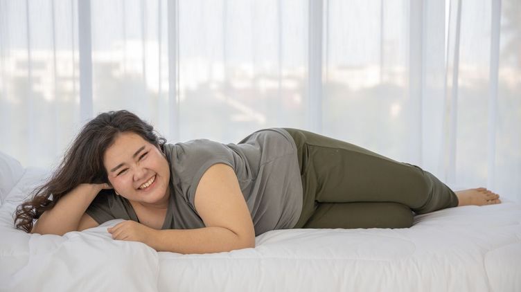 Plus-size Filipino woman smiling on white bed