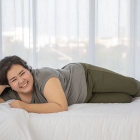 Plus-size Filipino woman smiling on white bed