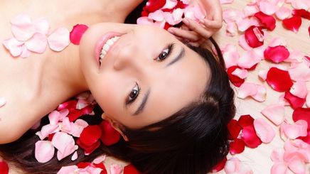 Asian woman laying on rose petals 
