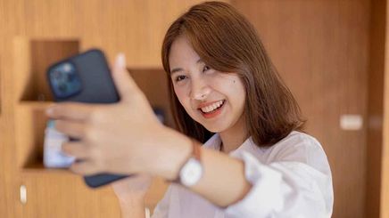 Smiling woman with shoulder-length brown hair taking a selfie. 