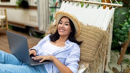 Asian lady using a laptop while sitting on a hammock