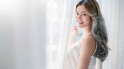  Asian woman by white curtain with gray hair.