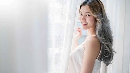  Asian woman by white curtain with gray hair.