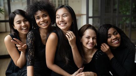 Five women of different ethnicities posing in their black dress