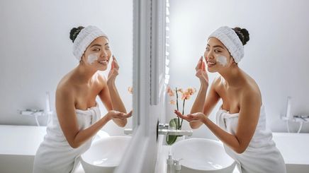 Asian woman applying skincare in the bathroom