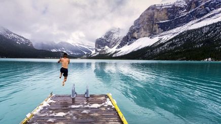 Asian man in shorts jumping into an icy lake.