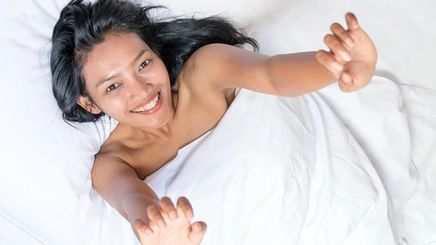 Asian woman with long hair in bed