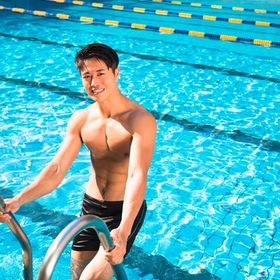 Smiling Asian man climbing out of pool.