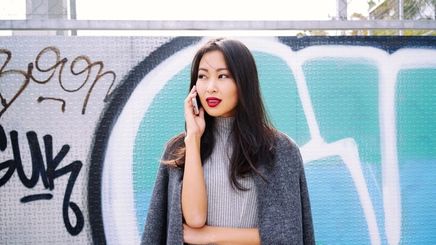Stylish Filipino woman wearing an outfit in different shades of gray, talking on the phone