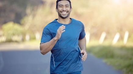 Asian man in a blue shirt running outdoors.