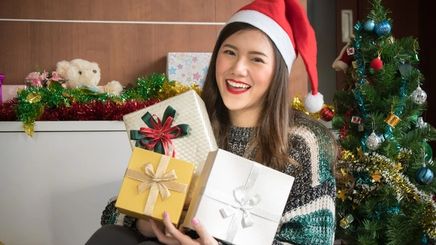 Happy Asian woman holding up Christmas gifts
