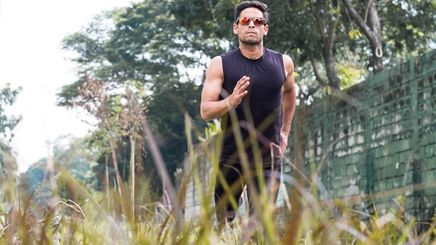 Fit Asian man in sunglasses running outdoors