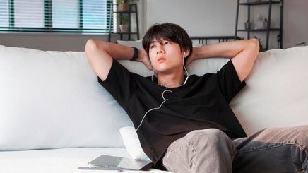 A portrait of man listening to music while sitting on a couch.