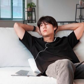 A portrait of man listening to music while sitting on a couch.