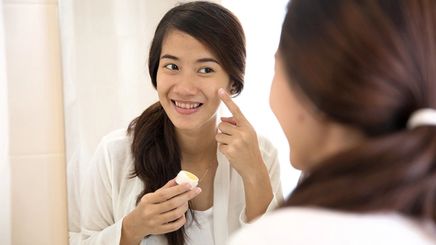 Asian woman applying skin cream 
