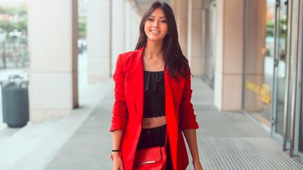 Woman in red blazer walking confidently down a corridor.