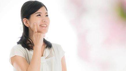 Asian woman touching smooth skin on cheek