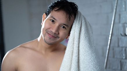 Young man wiping hair with towel