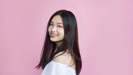 An Asian woman with long hair and white top smiling