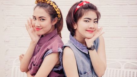Asian women smiling for a photo with cute headbands and retro outfits on.