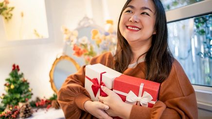 Happy Asian woman holding two Christmas gifts.
