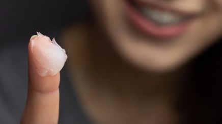 Closeup of young woman with petroleum jelly on finger