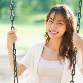 Happy Asian woman with long hair sitting on a swing.