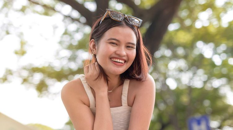 Filipino woman in white sleeveless top smiling outdoors