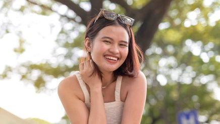 Filipino woman in white sleeveless top smiling outdoors