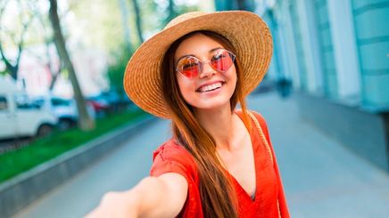 A portrait of smiling woman wearing sunglasses and sun hat.