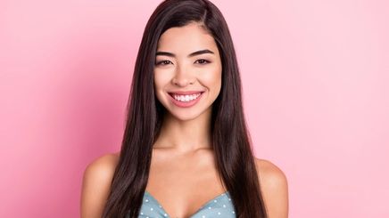 Young Asian woman with straight black hair against pink background
