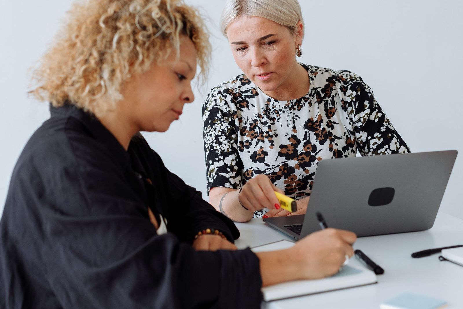 Two women over notes and a laptop