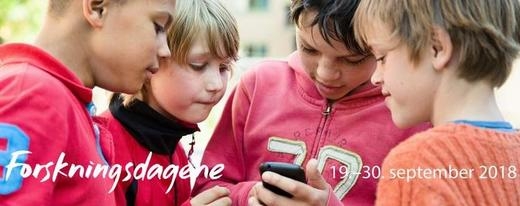 Fire gutter ser konsentrert på en mobil sammen. Forskningsdagene 2018 står over nederste del av bildet.