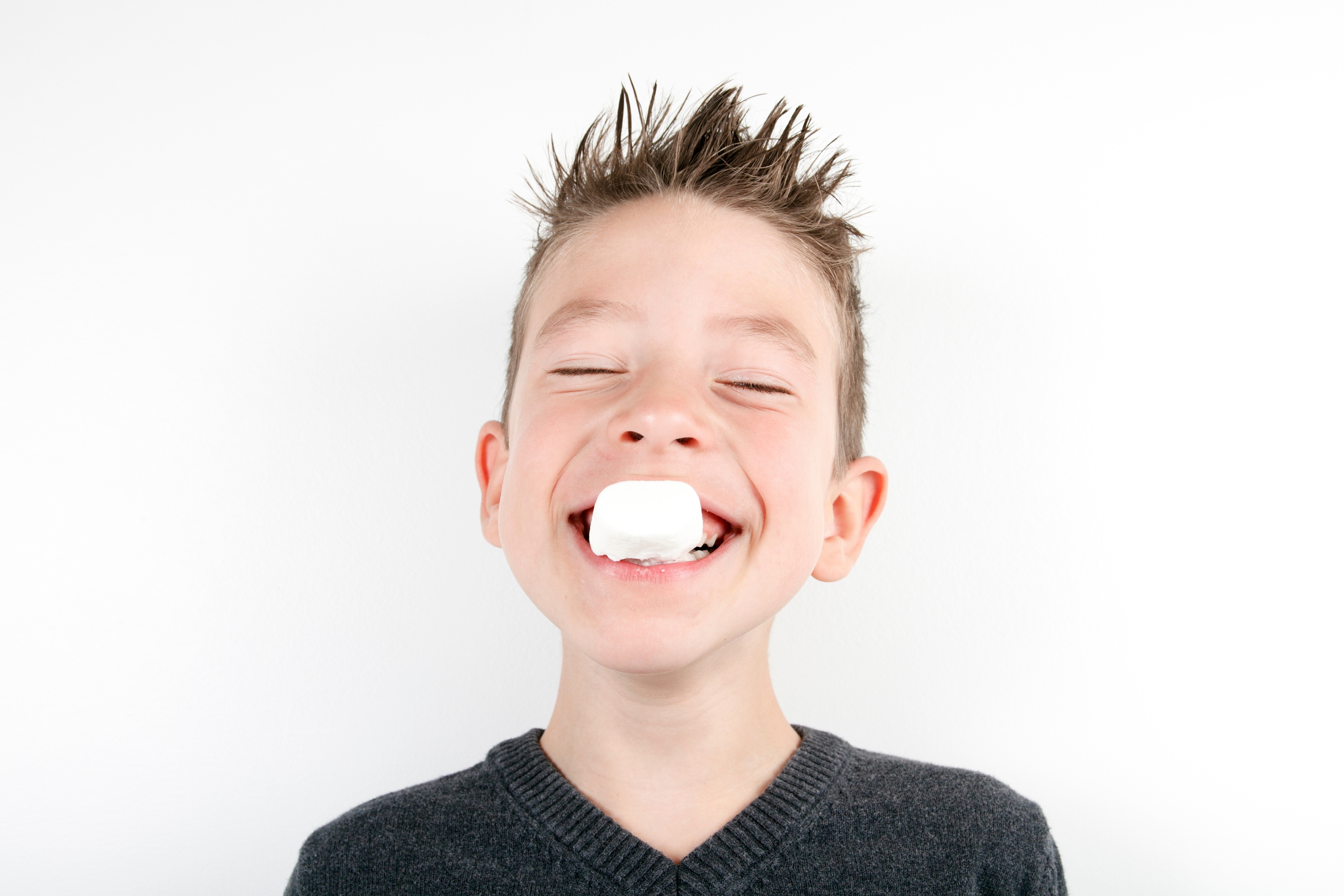 Smilende gutt med marshmallow i munnen.