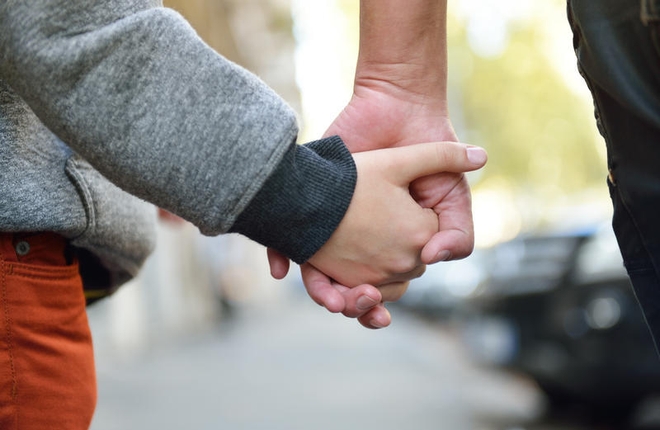 Barnehånd og voksenhånd leier hverandre.