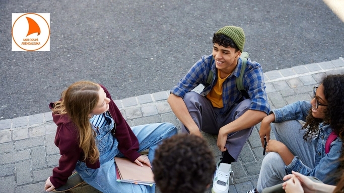 Fire ungdommer sitter i ring og snakker ute i skolegård.