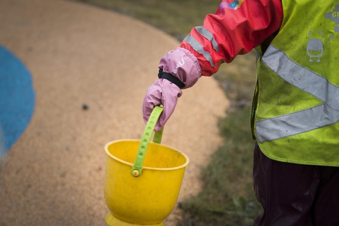 Barn i parkdress holder bøtte i hånda.