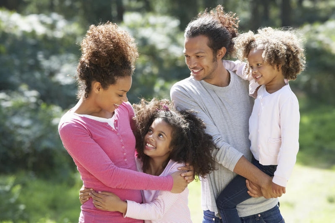 Glade foreldre med to døtre utendørs i skogen.