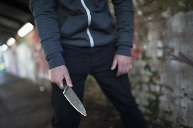 Ung mann med kniv i hånden i tunell.