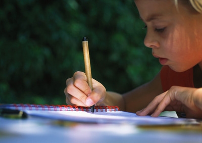 Barn skriver konsentrert i en kladdebok.