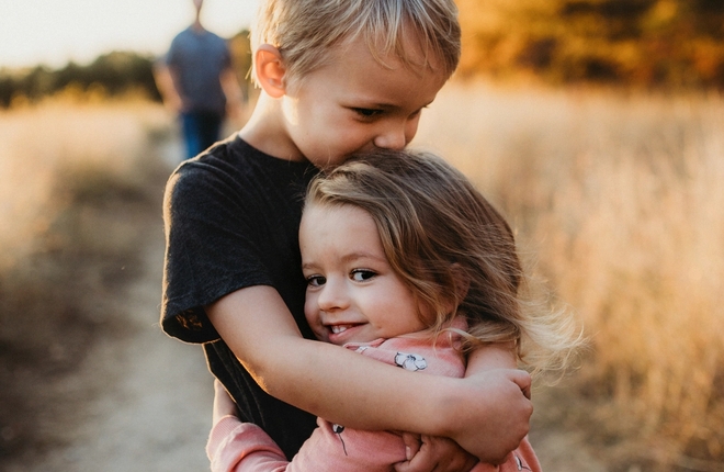To barn klemmer hverandre ut i natur på landevei.