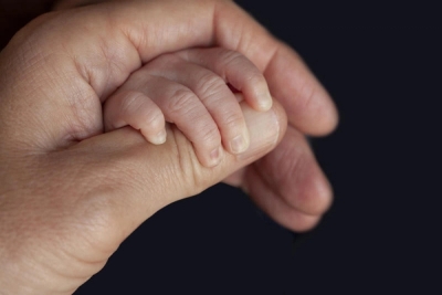 En voksens hånd holder en babys hånd.
