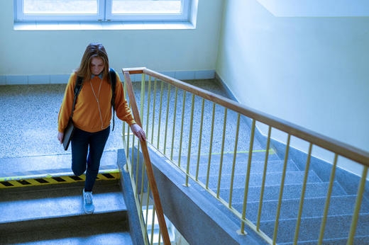 Tenåringsjente går ned trapp i skolebygg.
