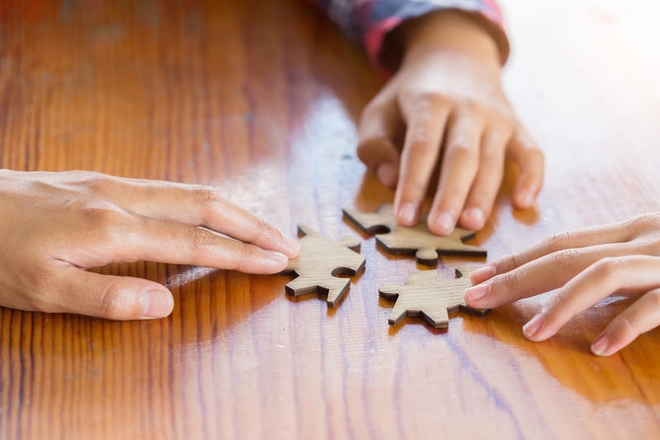 Barnehender og voksenhånd legger puslespill.