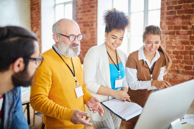 Fire kollegaer står samlet rundt en PC-skjerm.