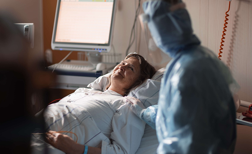 Kvinna är glad och ligger på sjukhussäng