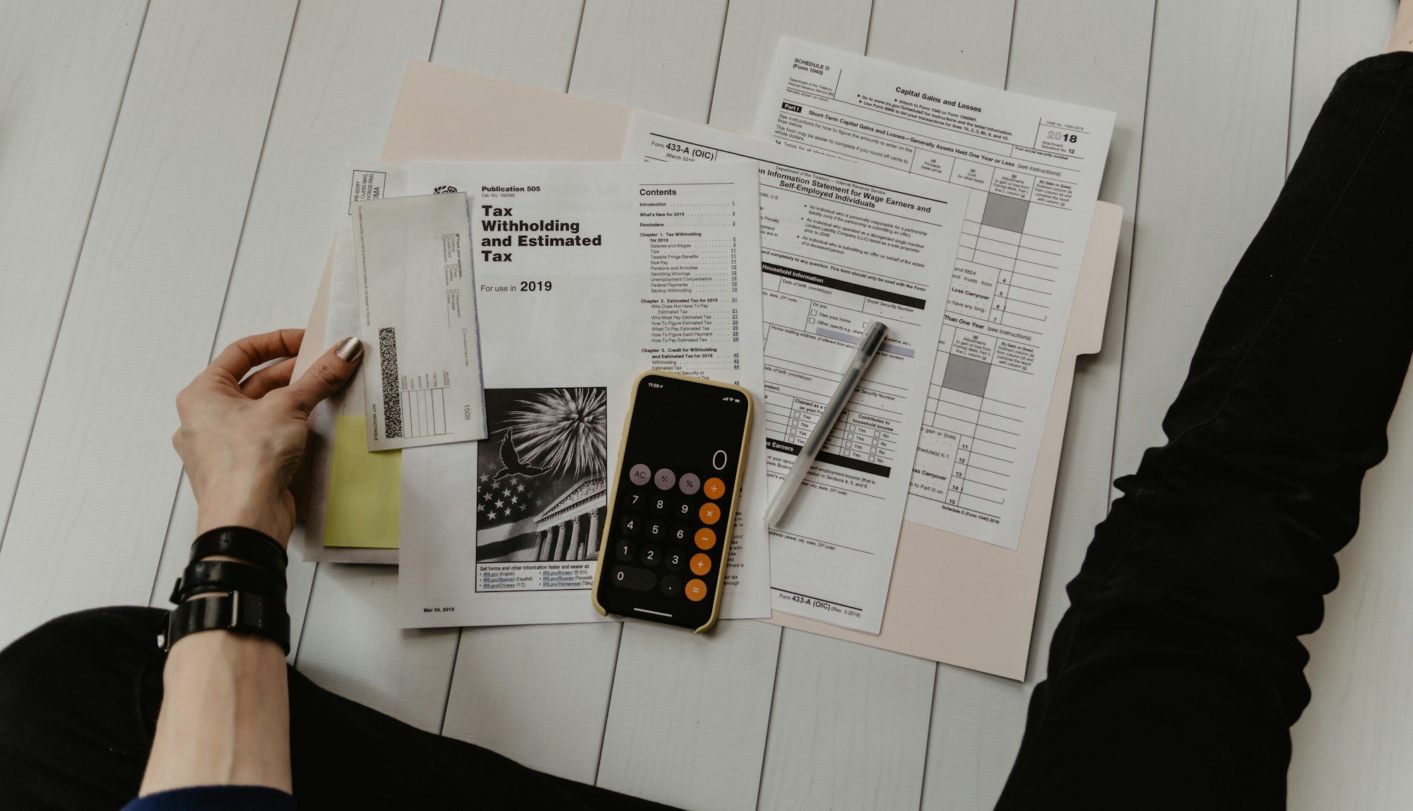 Calculatrice, stylo et documents de paie sur un bureau, pour illustrer le coût réel d'un salarié pour le gérant
