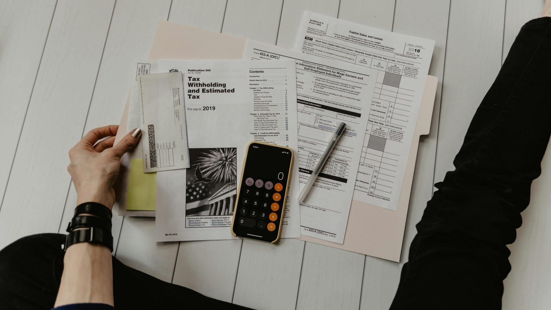 Calculatrice, stylo et documents de paie sur un bureau, pour illustrer le coût réel d'un salarié pour le gérant