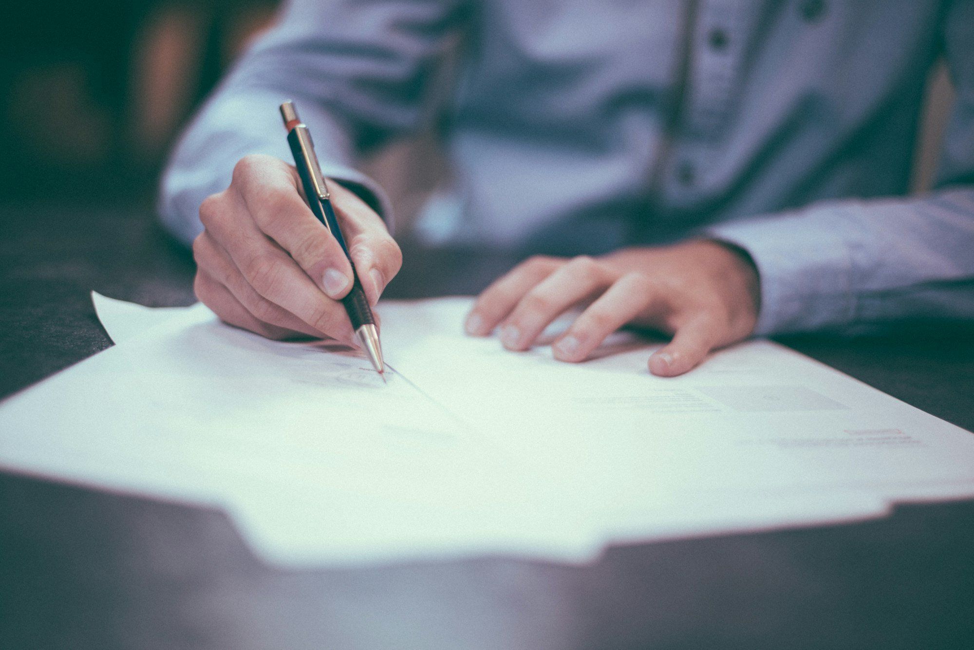 Personne signant un document fournisseur, stylo en main sur un bureau