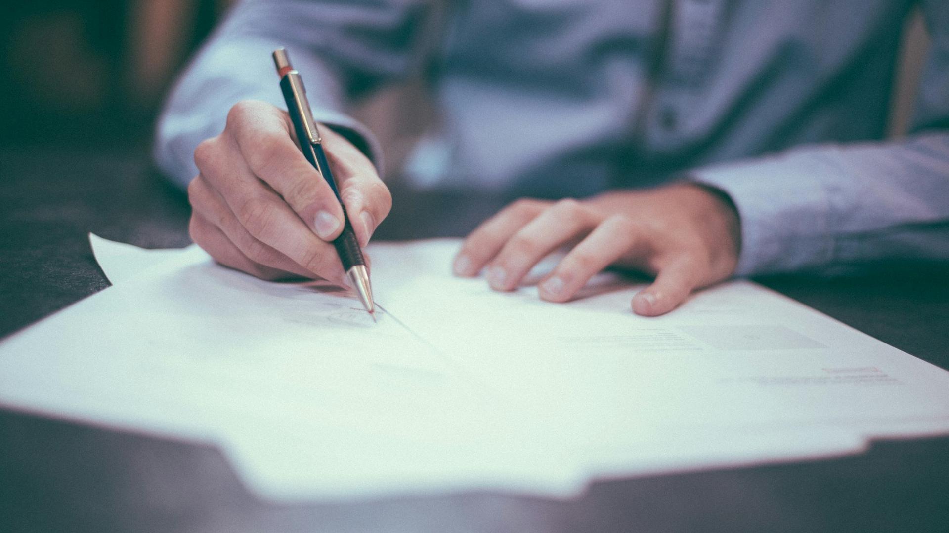 Personne signant un document fournisseur, stylo en main sur un bureau
